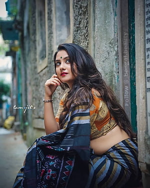Elegant Indian Woman in Traditional Saree Leaning Against Weathered Stone Wall HD phone wallpaper