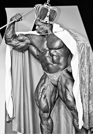 Ronnie Coleman in a black and white bodybuilding pose wearing a crown and royal cape HD phone wallpaper