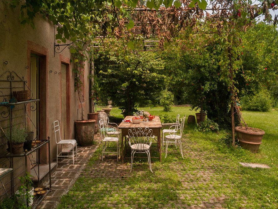 Rustic Garden Patio with Wrought Iron Furniture and Lush Greenery HD wallpaper