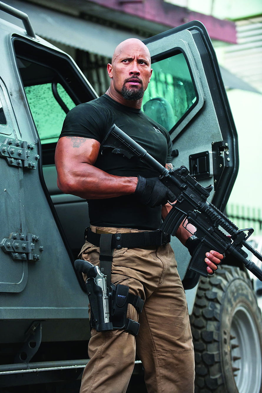 Dwayne Johnson as Deckard Shaw in Fast & Furious action scene with tactical rifle and armored vehicle HD phone wallpaper
