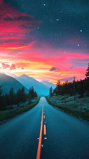 Empty Highway Stretching Toward Mountains Under a Vibrant Starry Sunset Sky HD phone wallpaper