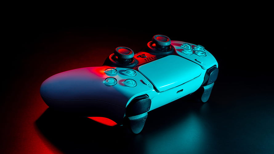 PlayStation 5 DualSense controller with red and blue neon lighting on a dark surface HD wallpaper
