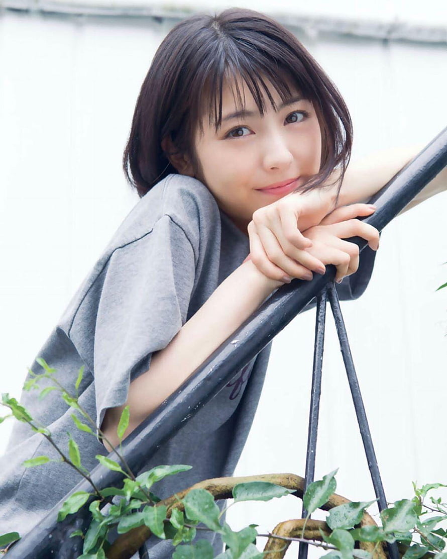 Minami Hamabe Leaning on a Railing with Green Foliage in a Soft Portrait HD phone wallpaper