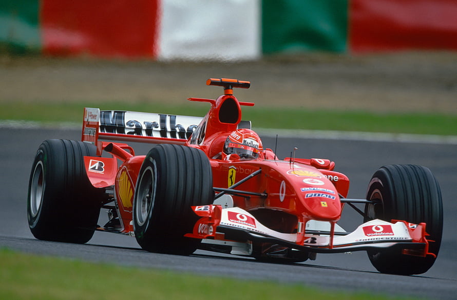 Michael Schumacher in the red Ferrari F2004 Formula 1 car on a race track HD wallpaper