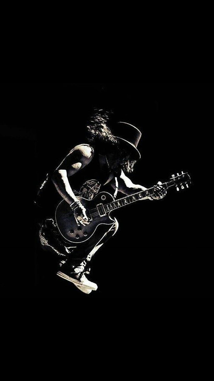 Slash from Guns N' Roses mid-air jump with electric guitar on dark stage HD phone wallpaper