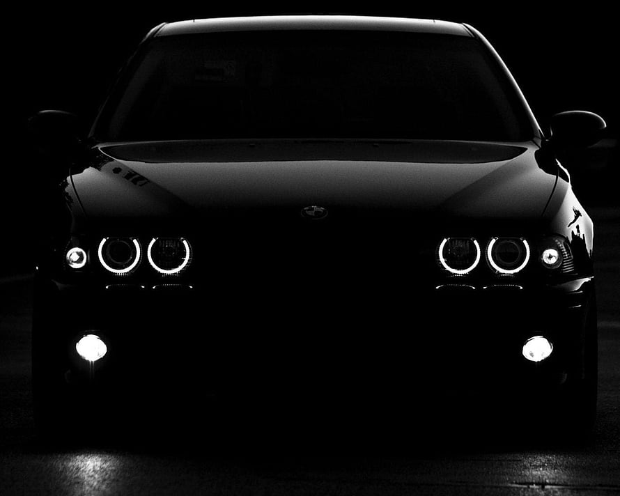 Black and White Front View of a BMW M5 with Angel Eyes Headlights in Darkness HD wallpaper