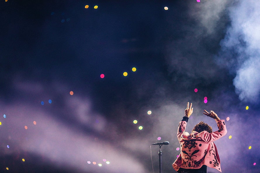Harry Styles performing on stage with colorful bokeh lights and atmospheric smoke HD wallpaper