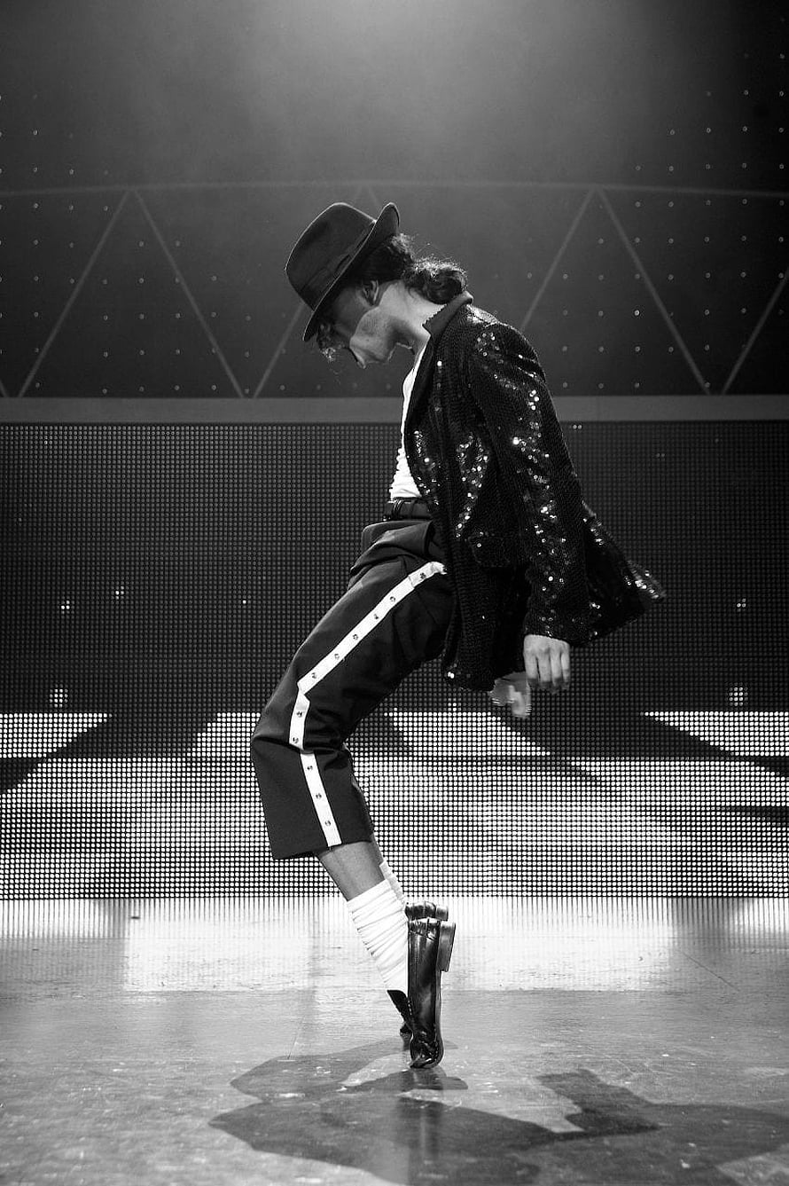 Michael Jackson performing a signature dance move on stage in a sequined jacket and fedora HD phone wallpaper