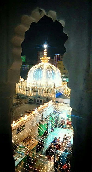 Ajmer Dargah Sharif illuminated dome at night viewed through an ornate archway HD phone wallpaper