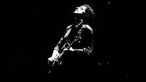 Gustavo Cerati performing on stage with electric guitar in dramatic black and white lighting HD wallpaper