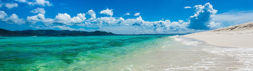 Turquoise Ocean Water Lapping Against White Sand Beach Under Blue Sky HD wallpaper