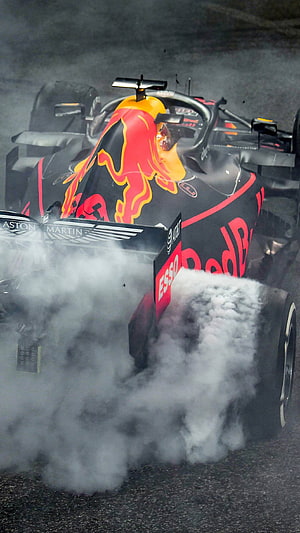 Red Bull Racing Formula 1 car drifting through thick tire smoke on the track HD phone wallpaper