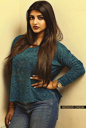Sreeleela in a teal knit top and blue jeans posing against a beige wall HD phone wallpaper