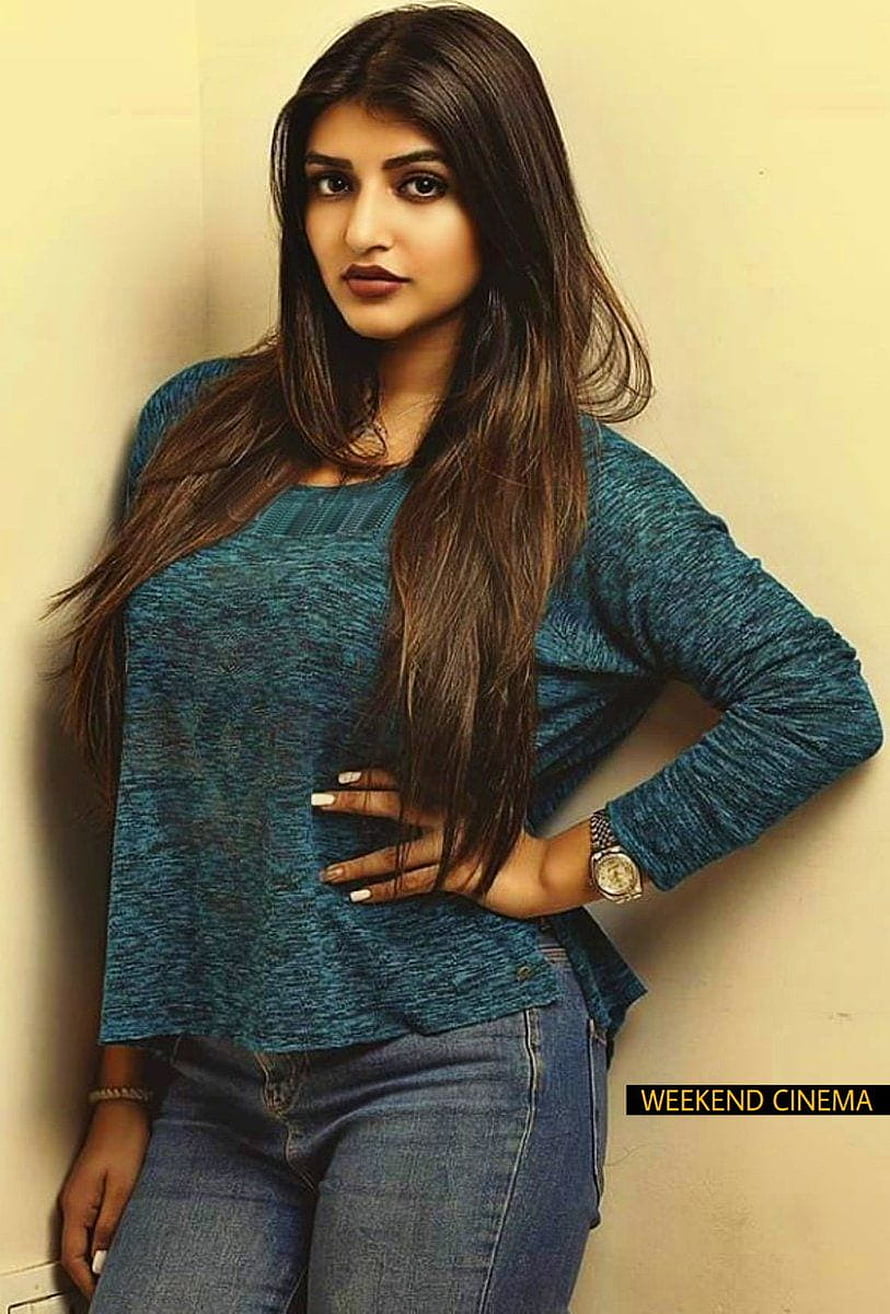 Sreeleela in a teal knit top and blue jeans posing against a beige wall HD phone wallpaper