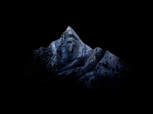 Snow-Capped Mountain Peak Rising from Darkness in Dramatic Nighttime Landscape HD wallpaper