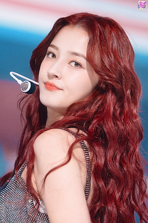 Nancy from MOMOLAND with long wavy red hair and a stage headset microphone HD phone wallpaper