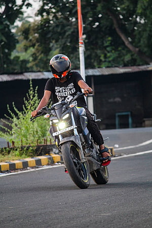 Rider on a Yamaha MT15 Motorcycle Performing a Wheelie on a Paved Road HD phone wallpaper