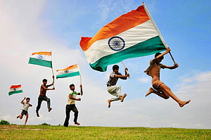 Indian Youth Jumping With National Flag On Green Grassland Under Blue Sky HD wallpaper