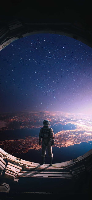 Interstellar astronaut standing at a space station viewport overlooking a glowing planet and starry cosmos HD phone wallpaper