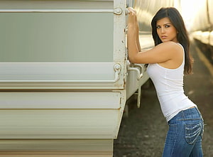 Sunny Leone in white tank top and jeans leaning against a truck HD wallpaper