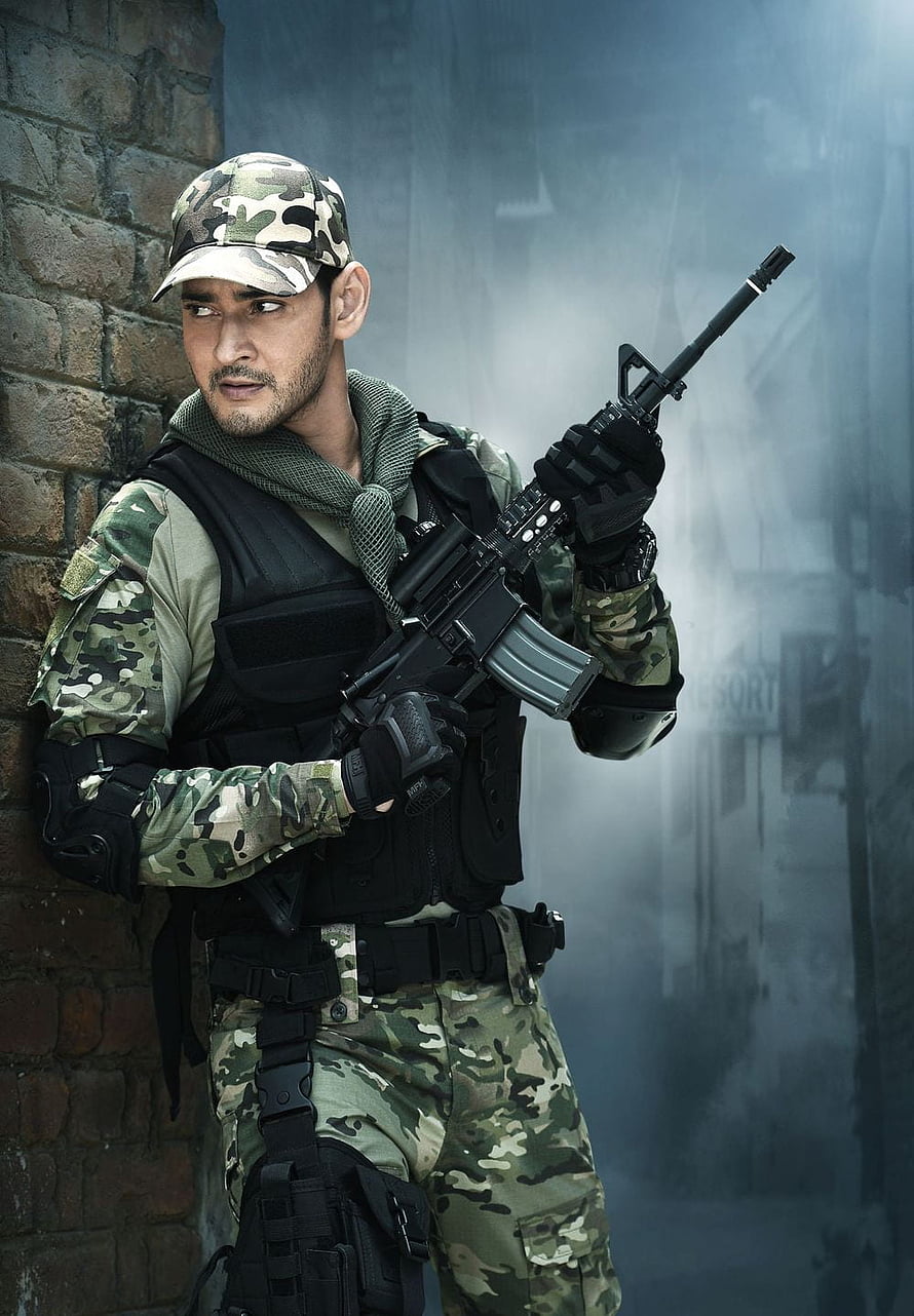 Mahesh Babu in military camouflage uniform holding assault rifle in smoky urban setting HD phone wallpaper