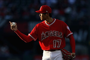 Shohei Ohtani in Los Angeles Angels uniform holding a baseball on the field HD wallpaper