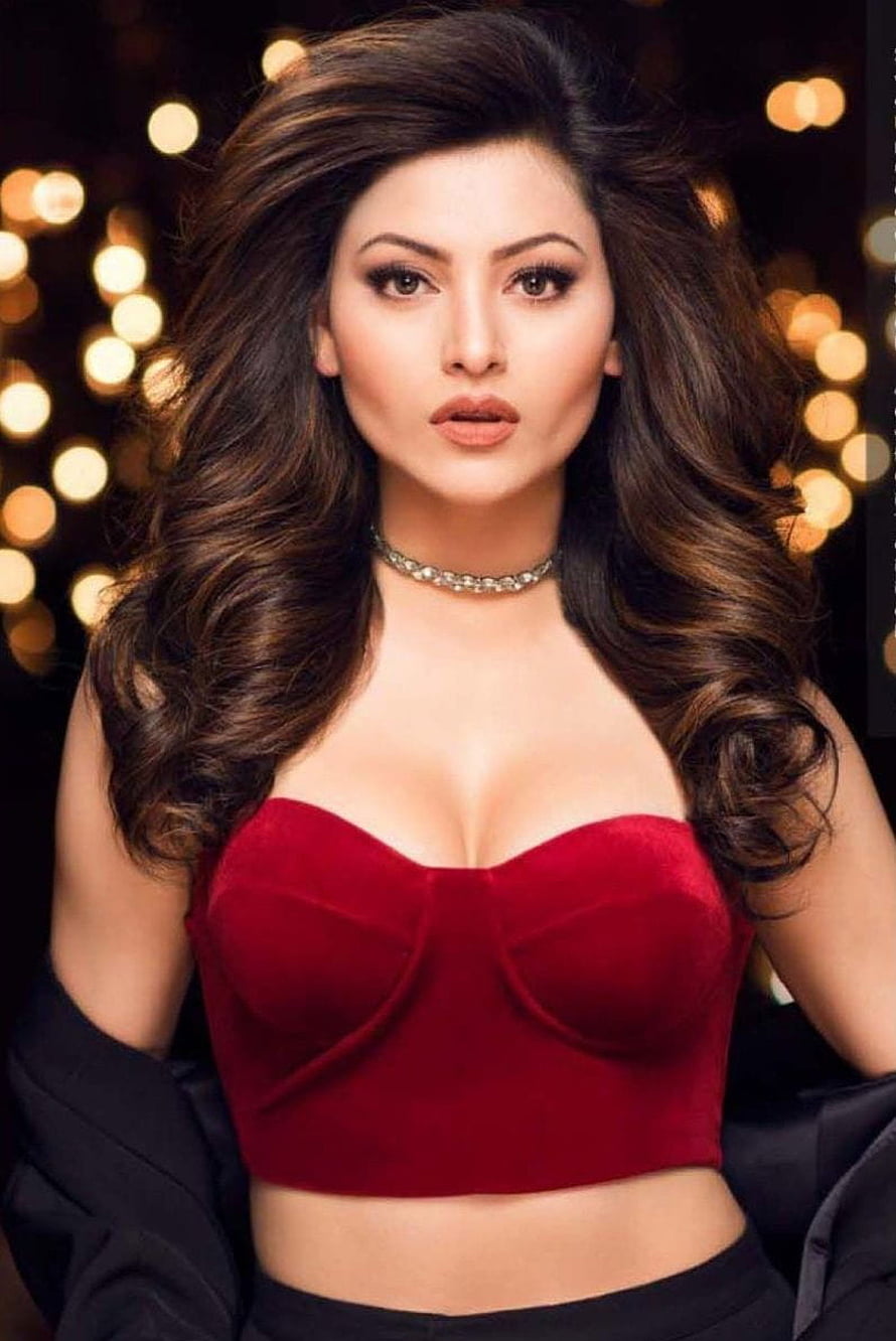 Urvashi Rautela in a red velvet crop top with a black blazer against a warm bokeh background HD phone wallpaper