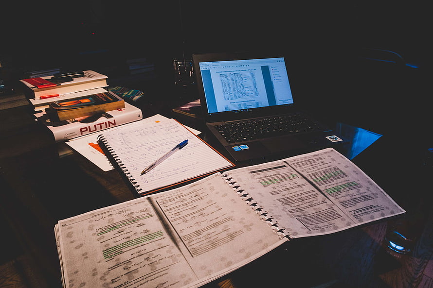 Cozy Late Night Study Session With Open Notebook, Laptop, and Stacked Books on a Dark Desk HD wallpaper