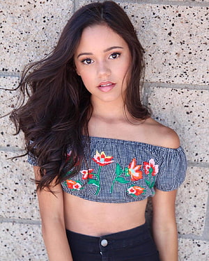 Jenna Ortega in Off-Shoulder Floral Crop Top and Black Jeans Against Stone Wall HD phone wallpaper