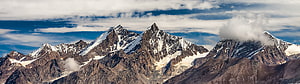 Majestic Snow-Capped Mountain Range Under a Dramatic Cloudy Sky HD wallpaper