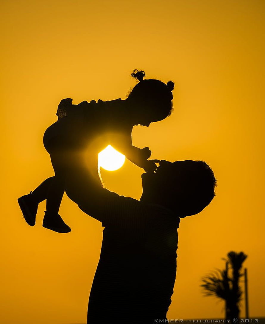 Silhouette of a father lifting his daughter against a golden sunset sky HD phone wallpaper