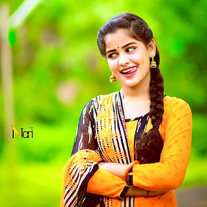 Meghana Raj in a yellow kurta and patterned dupatta with a long braid against a green background HD phone wallpaper