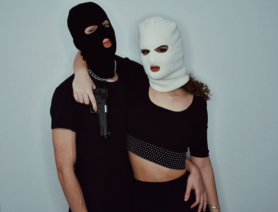 Couple in Black and White Ski Masks Holding a Pistol Against a Grey Background HD wallpaper