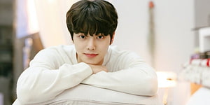 Song Kang in a White Sweater Leaning on a Cushion in a Bright Indoor Setting HD wallpaper
