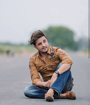 R Nait Sitting on Asphalt Road in Casual Brown Shirt and Jeans HD phone wallpaper