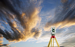 Total Station Surveying Instrument on Tripod Against Dramatic Sunset Sky HD wallpaper