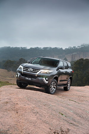 Toyota Fortuner SUV Parked on Rocky Outcrop in Misty Mountain Landscape HD phone wallpaper