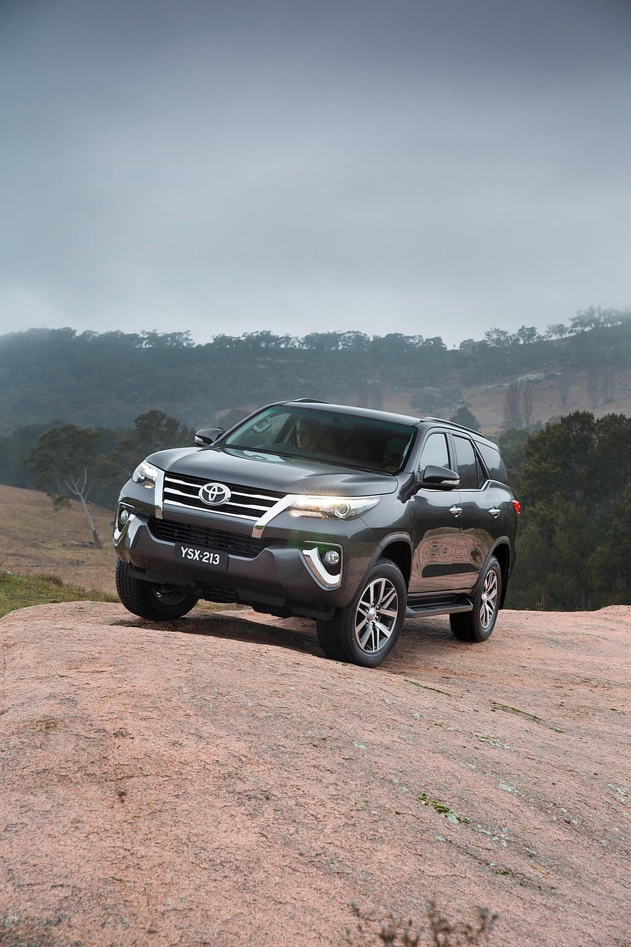 Toyota Fortuner SUV Parked on Rocky Outcrop in Misty Mountain Landscape HD phone wallpaper