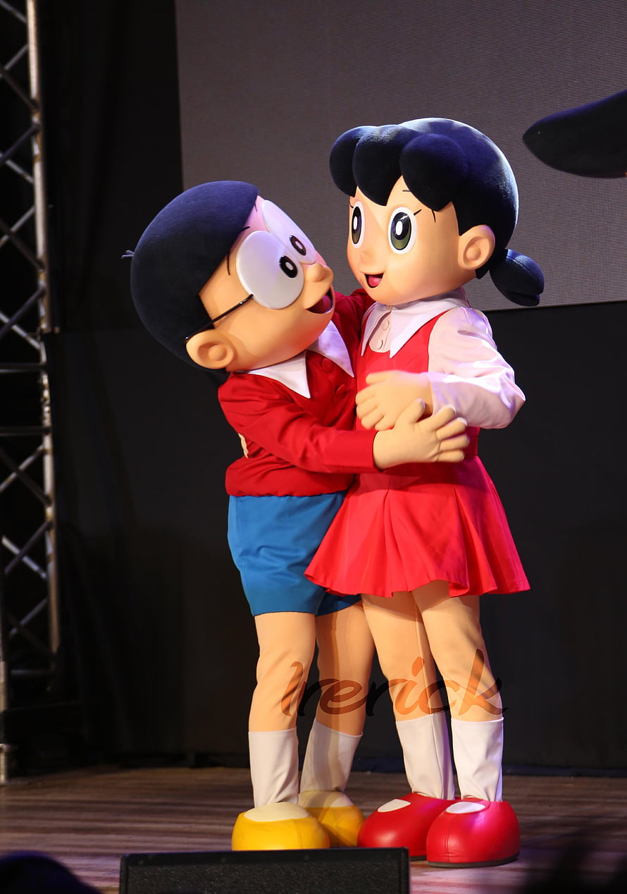 Nobita and Shizuka Character Costumes Embracing on Stage HD phone wallpaper