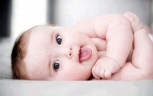 Adorable Baby Boy Lying Down with Tongue Out in Soft Natural Light HD wallpaper