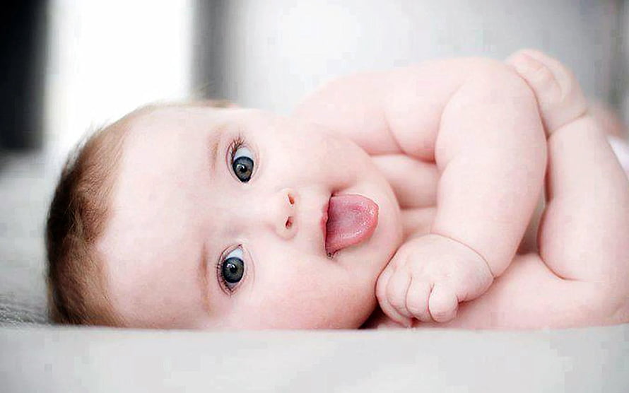 Adorable Baby Boy Lying Down with Tongue Out in Soft Natural Light HD wallpaper