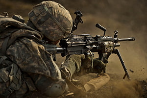 Soldier in digital camouflage firing a mounted machine gun in a dusty combat environment HD wallpaper