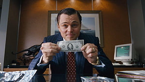 Leonardo DiCaprio as Jordan Belfort in The Wolf of Wall Street holding a dollar bill in a luxury office HD wallpaper
