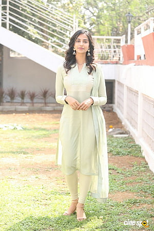 Meenakshi Chaudhary in a pastel green embroidered kurta and dupatta standing outdoors HD phone wallpaper