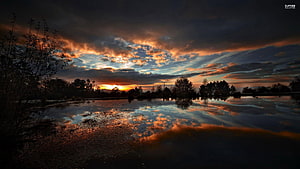 Dramatic Sunset Over a Calm Lake with Vivid Cloud Reflections HD wallpaper