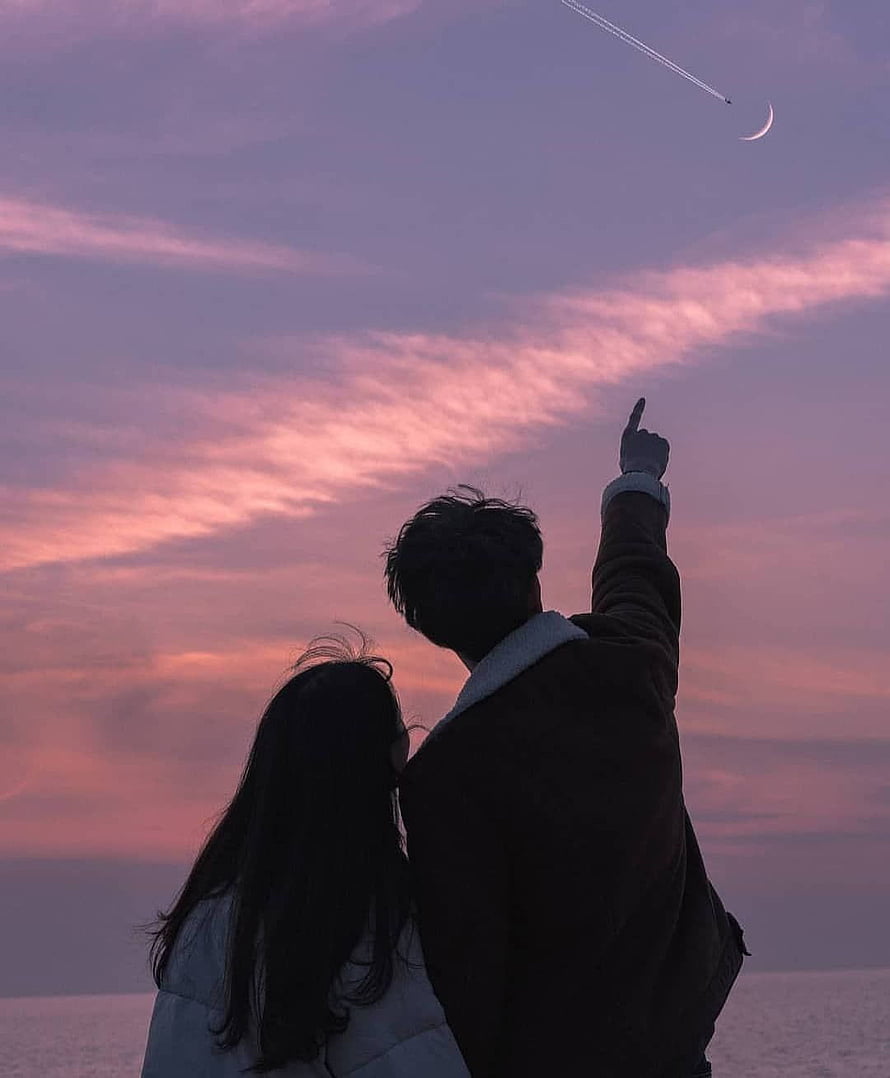 Silhouetted couple pointing at a crescent moon and airplane trail in a pink sunset sky HD phone wallpaper