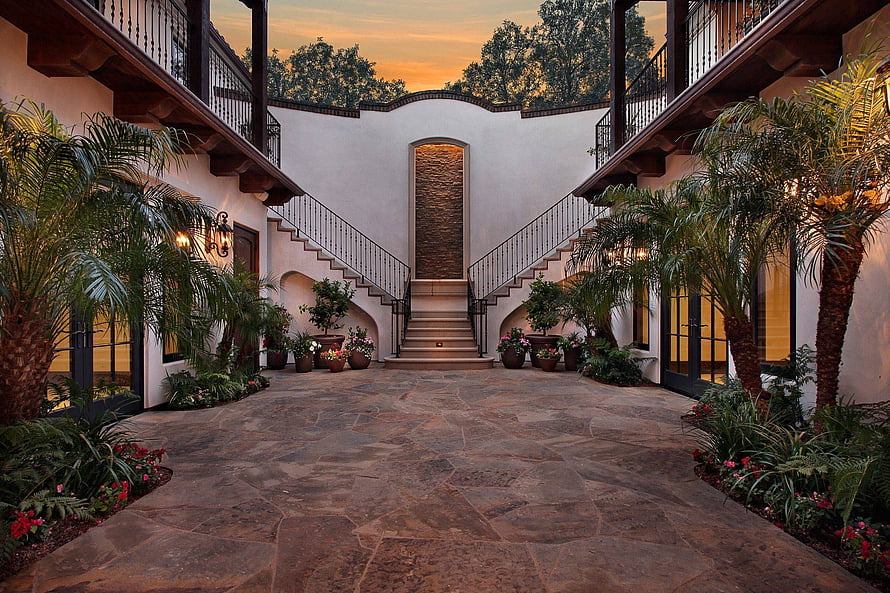 Modern Hacienda Courtyard with Split Staircase and Lush Tropical Landscaping at Sunset HD wallpaper