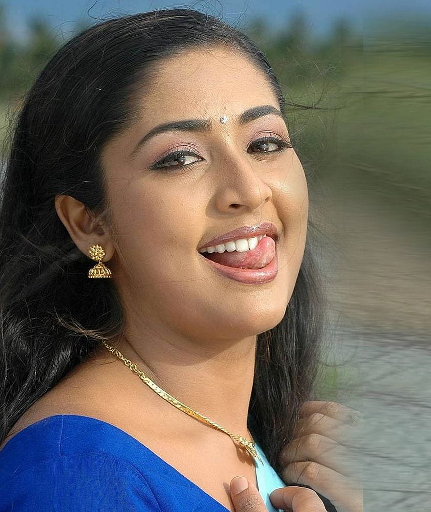 Navya Nair in a blue off-shoulder top with gold jewelry and a playful expression HD phone wallpaper
