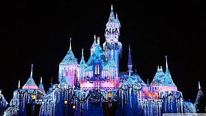 Illuminated Fairy Tale Castle at Night with Festive Holiday Lights and Sparkling Blue and Pink Glow HD wallpaper