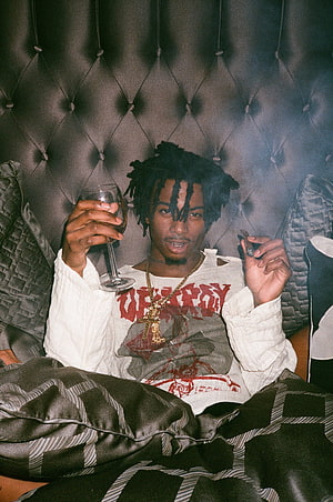Young Rapper Holding Wine Glass and Cigarette on Tufted Headboard HD phone wallpaper
